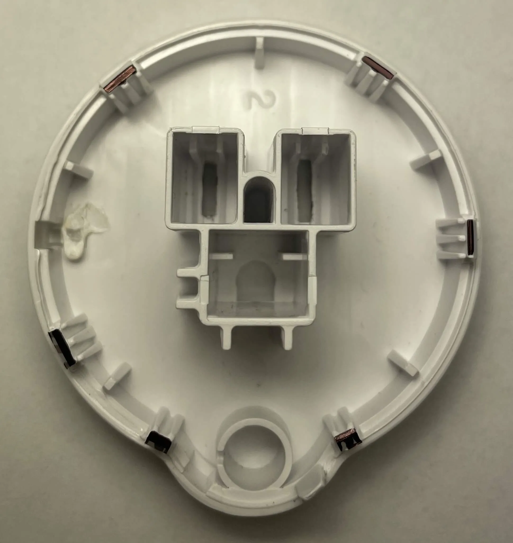 Etekcity Voltson ESW01-USA-R6P Shell Clips Back View A top-down back view of the inside of the front shell of an Etekcity Voltson ESW01-USA-R6P Smart Outlet. There are black marks on each of the six clips of the plastic shell. The clips are positioned clockwise at 35°, 90°, 155°, 205°, 240°, and 320°.